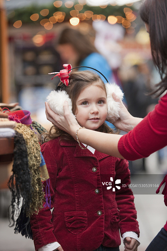 一位妇女在假日购物时给女儿戴上耳套图片素材