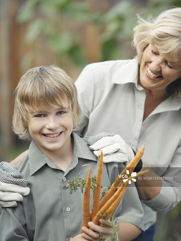 女人和男孩在花园里种胡萝卜图片素材