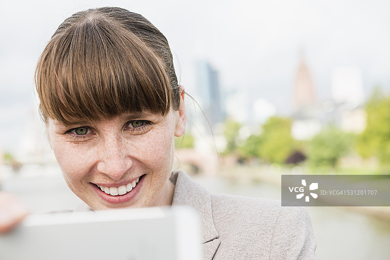 德国，黑森州，法兰克福，带着平板电脑微笑的女商人的肖像图片素材
