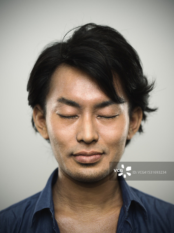 一个年轻的日本男子闭着眼睛的肖像。图片素材