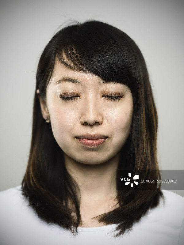 一个放松的年轻日本妇女的肖像闭着眼睛。图片素材