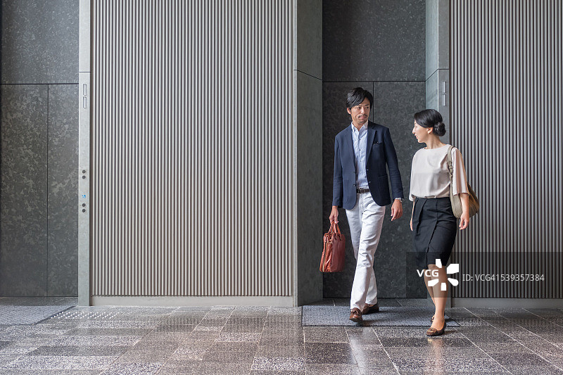 日本商人和女商人走出现代办公大楼的电梯图片素材
