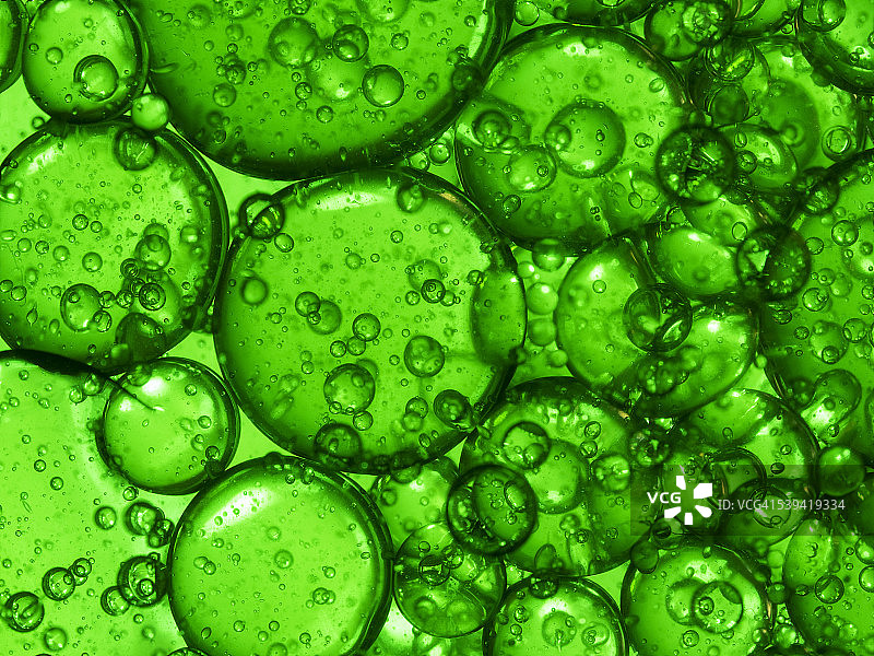 油滴和气泡漂浮在水面上，背景是绿色的图片素材