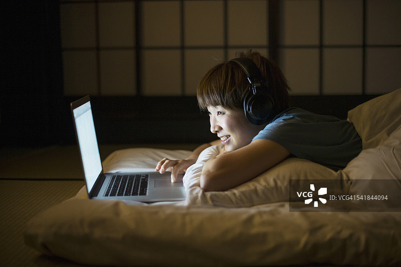 一个女人在床上用笔记本电脑图片素材