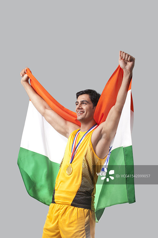 男性奖牌获得者在灰色背景下举着印度国旗庆祝胜利图片素材