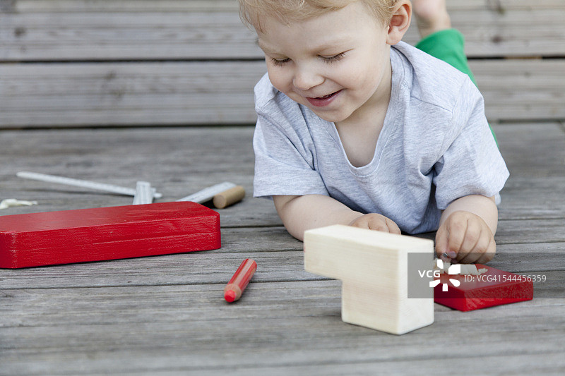男孩蹒跚学步玩木块玩具船在码头图片素材