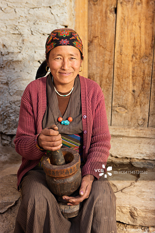 西藏妇女用研钵做面粉。野马、尼泊尔图片素材