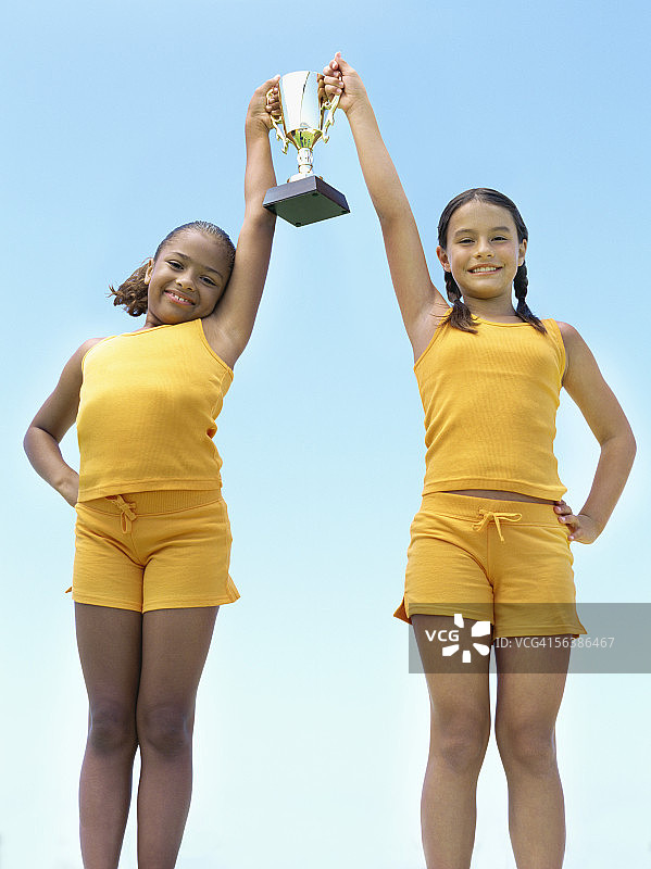 低角度的两个女孩举着奖杯图片素材