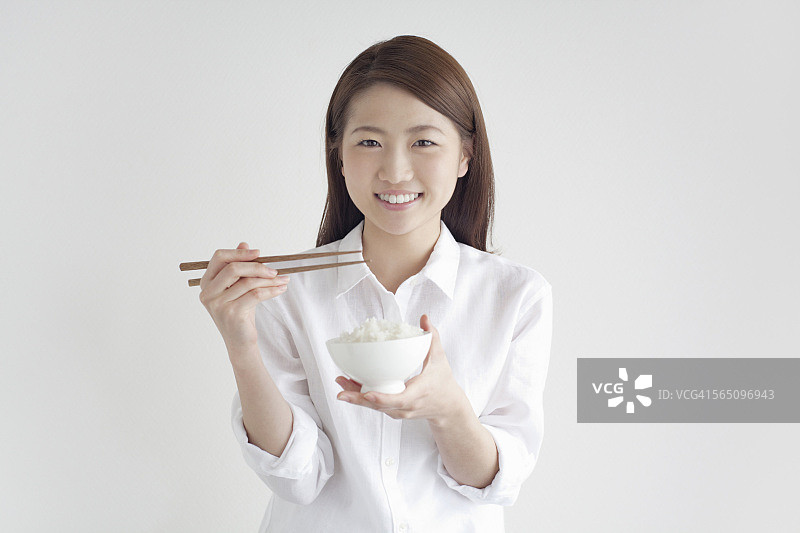 年轻女子用筷子吃一碗米饭图片素材