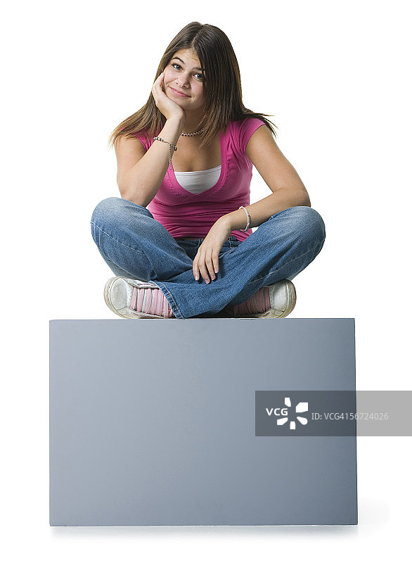 一个十几岁的女孩坐在一个空白的标牌上思考图片素材