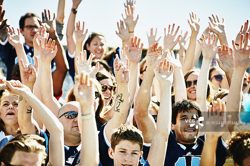 球迷们高举手臂在体育场欢呼图片素材