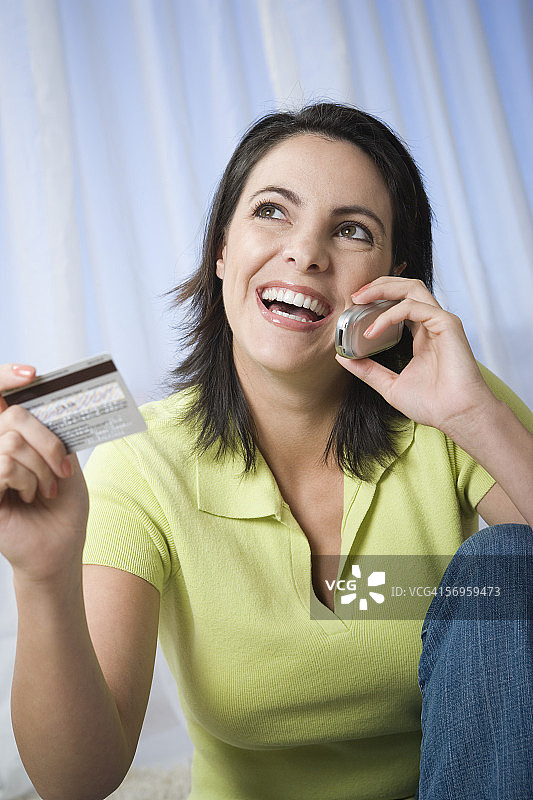 一个中年妇女的特写，谈论一个手持信用卡的手机图片素材