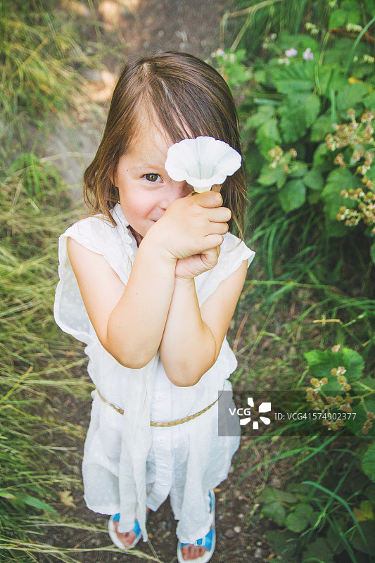 女孩把一朵花举在面前图片素材