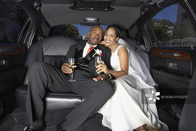 新婚夫妇在豪华轿车里喝香槟图片素材