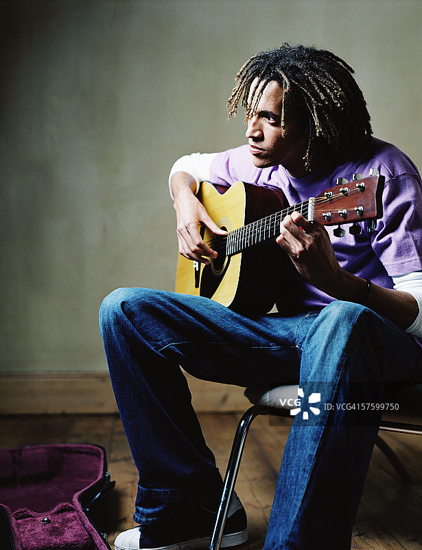 一个弹吉他的年轻人的侧面照片图片素材