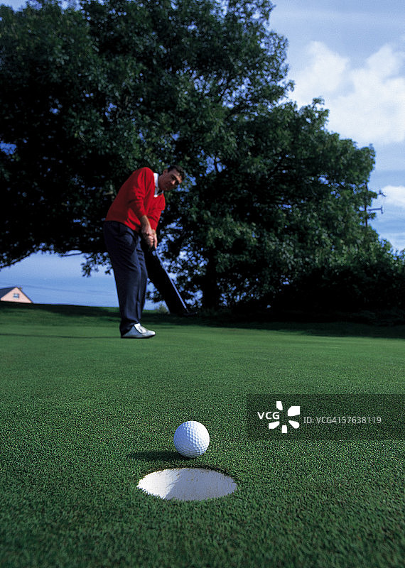 一个高尔夫球手把球击向洞的低角度视图图片素材