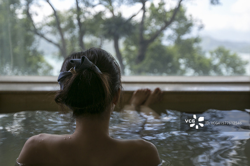 一个年轻的女人享受日式温泉与美丽的风景图片素材