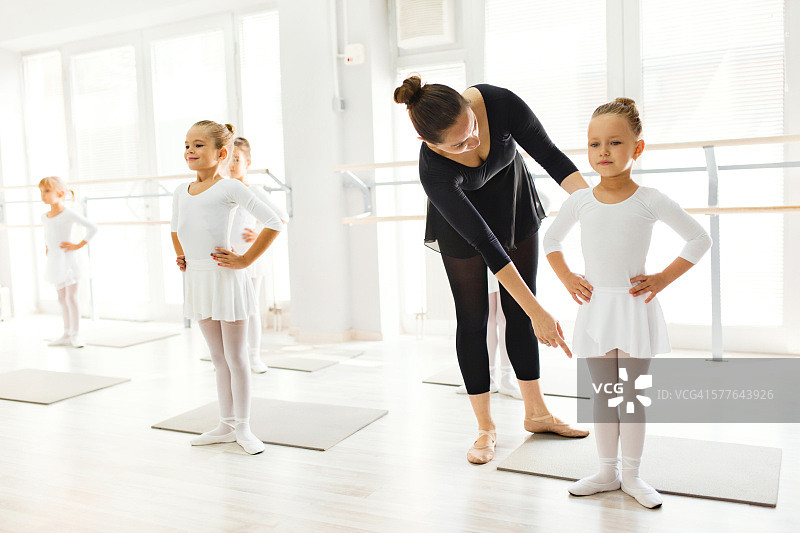 芭蕾舞老师在芭蕾课上帮助女孩们练习姿势。图片素材