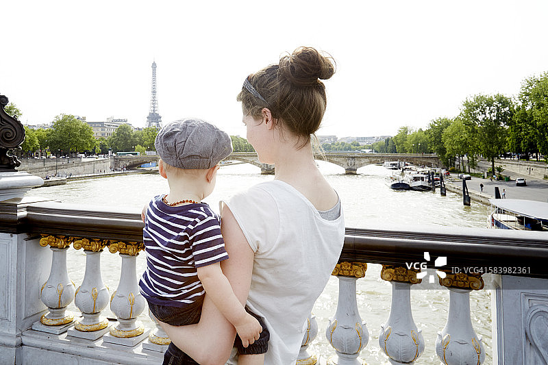 妈妈和蹒跚学步的男孩在巴黎面对埃菲尔铁塔图片素材