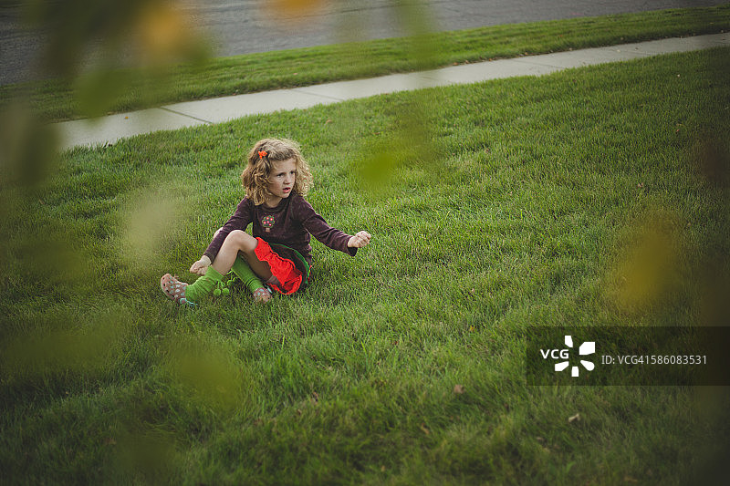 小女孩坐在绿色的草地上图片素材