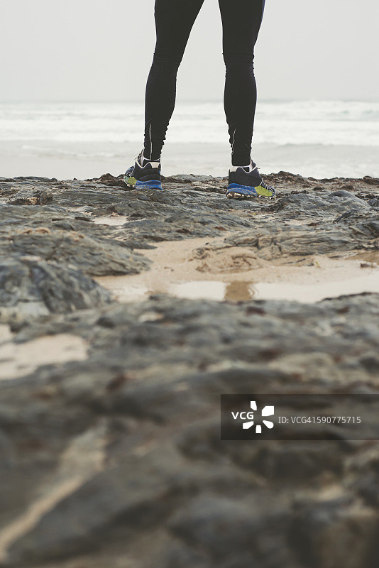 海滩岩石上慢跑者的腿图片素材