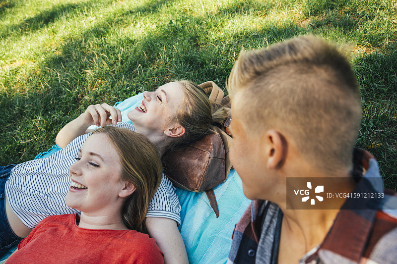 三个青少年朋友在草地上放松图片素材