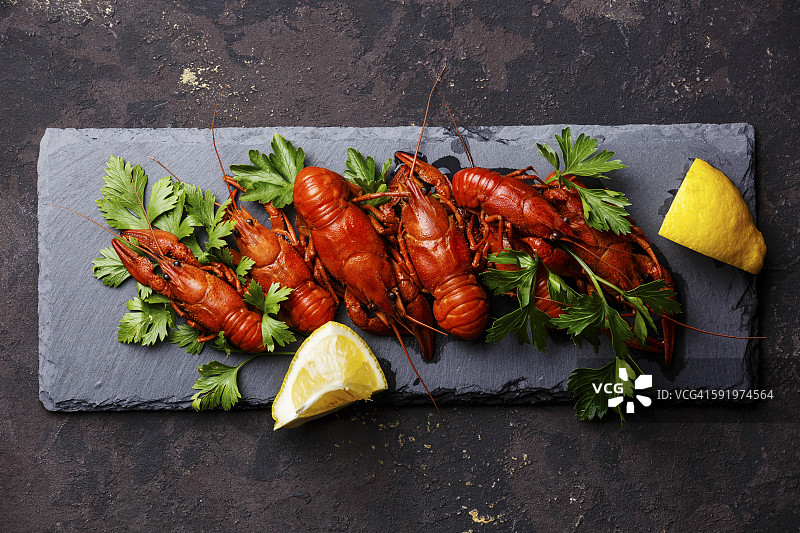 红色水煮小龙虾与柠檬石板在黑暗的背景图片素材