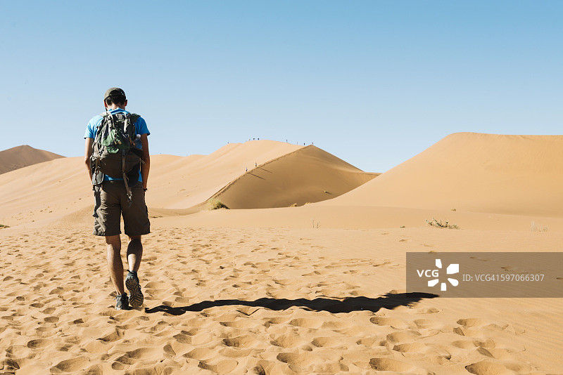 纳米比亚，纳米布沙漠，背着背包的男人走过沙丘图片素材