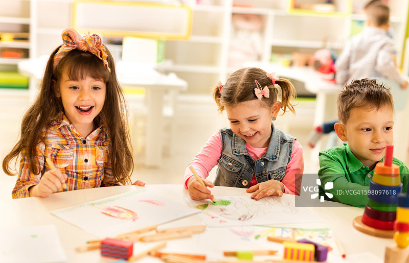 微笑的小女孩和她的朋友们在幼儿园素描。图片素材