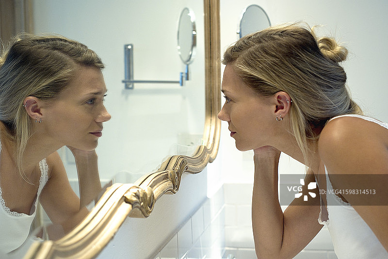 一个女人在浴室镜子里看着自己图片素材