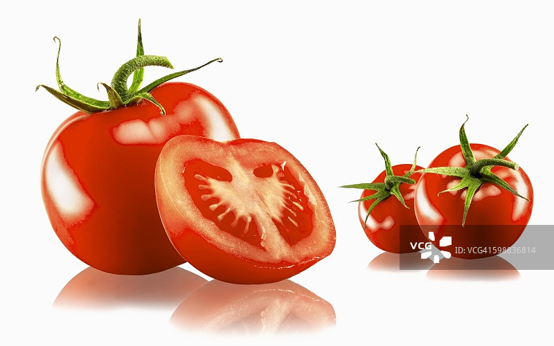 三个完整的和一个对半切的番茄，有白色的背景和倒影图片素材