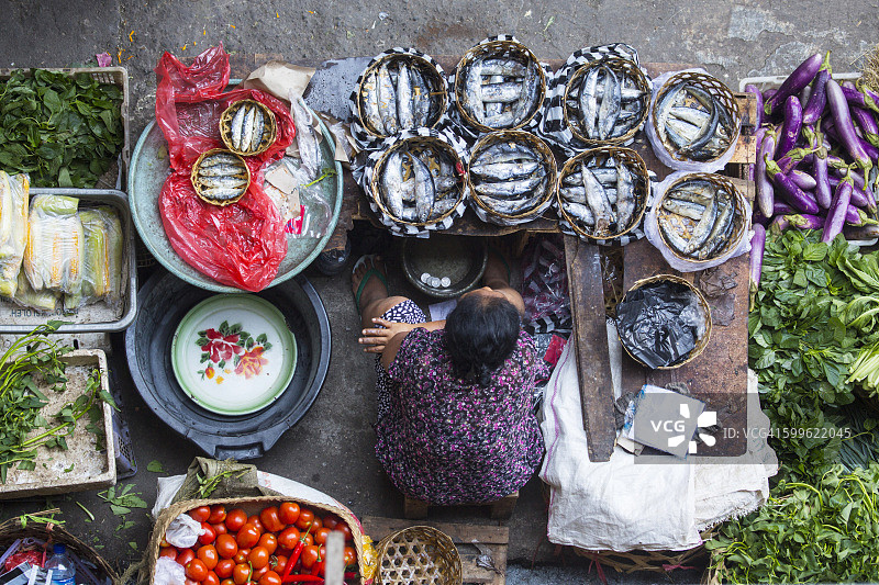 印尼巴厘岛乌布，传统市场上的小贩，手里拿着装满鱼的篮子图片素材