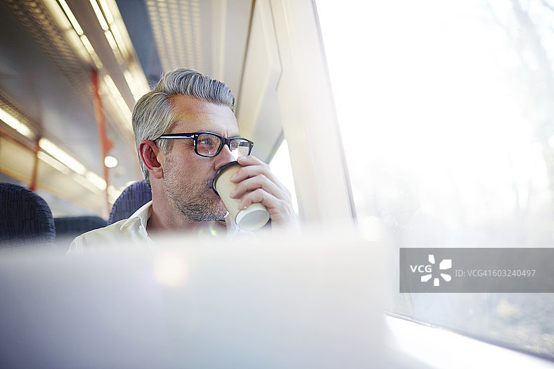在通勤火车上喝咖啡的商人。图片素材