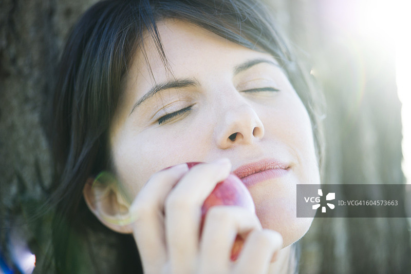 一个女人把苹果贴在脸上，闭着眼睛图片素材