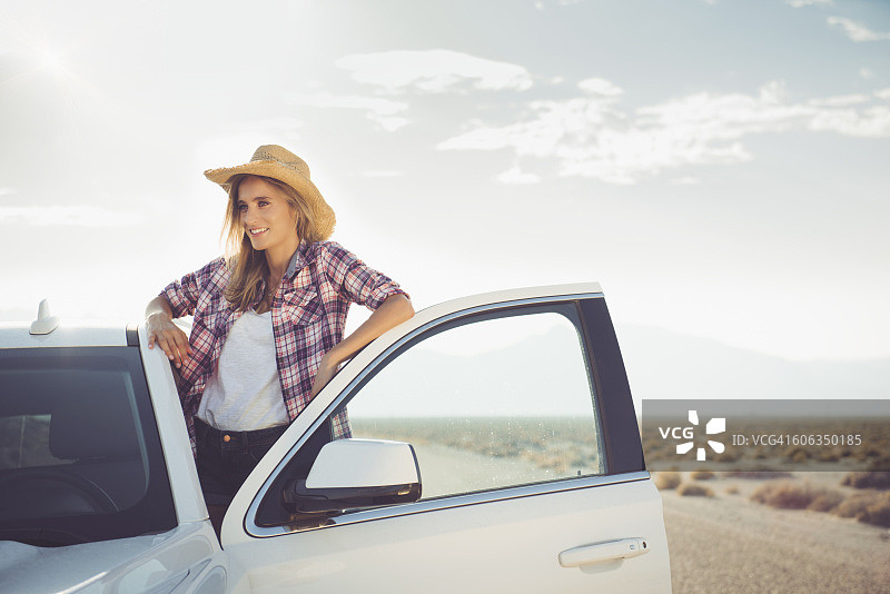 一名西班牙妇女站在偏远公路上的车里图片素材