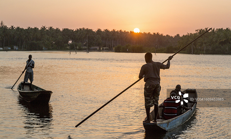 日落时分，在非洲象牙海岸的阿比让，当地男子在水上划船图片素材