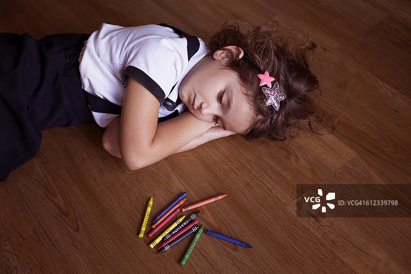 女孩躺在地板上，手里拿着蜡笔图片素材