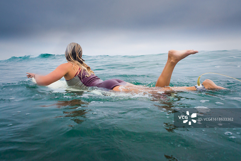 女冲浪者在日出时划入海洋图片素材