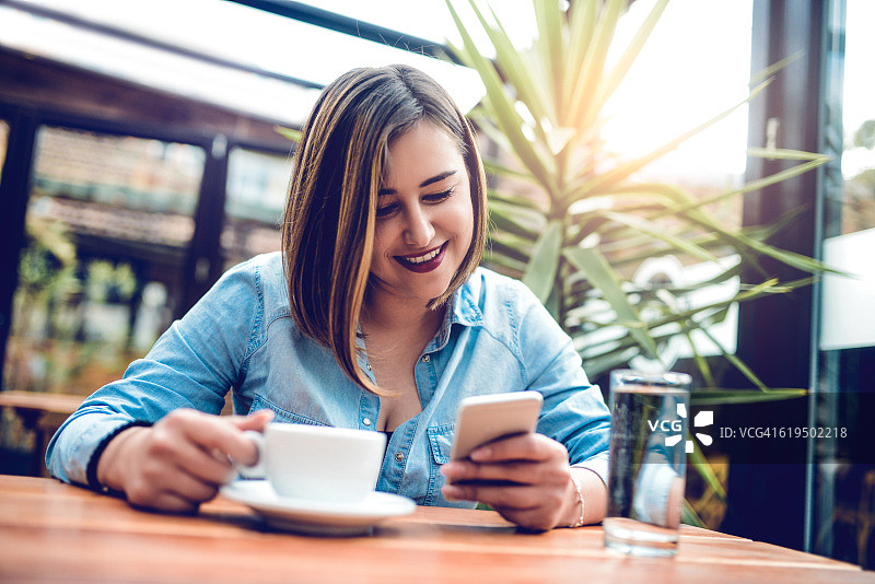 年轻女性在她最喜欢的咖啡店使用智能手机图片素材