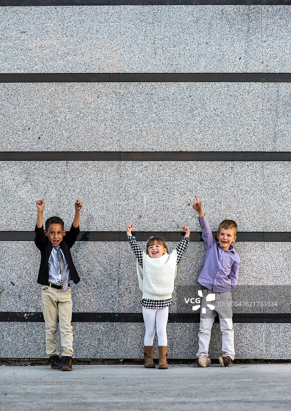一群成功的商业小孩靠在墙上。图片素材