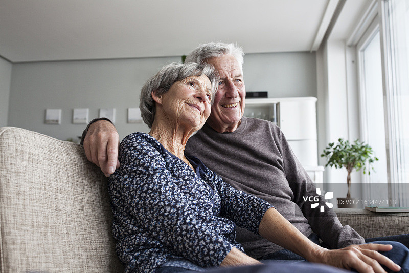 一对快乐的老年夫妇一起坐在客厅的沙发上图片素材