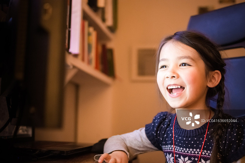 快乐的小女孩在家里用电脑图片素材