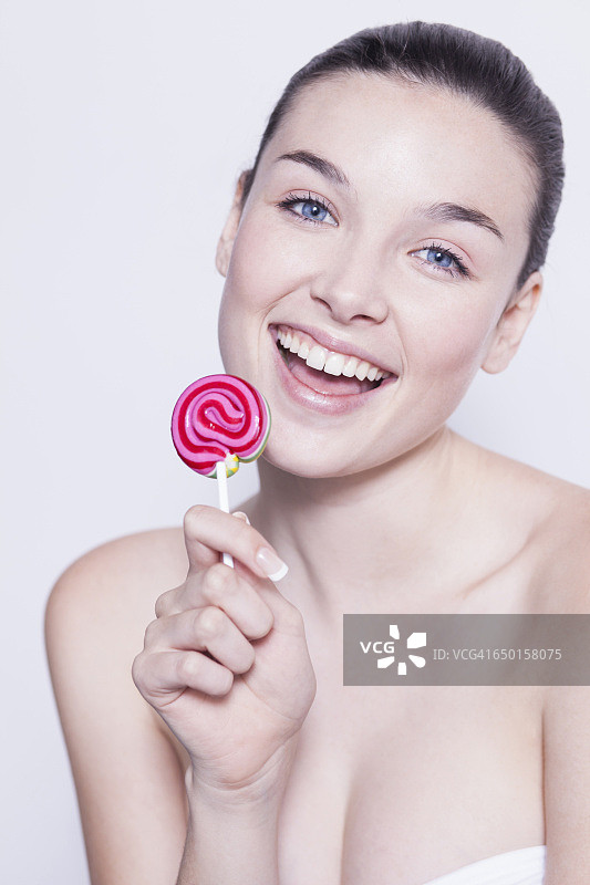 美丽的年轻女子手持粉色棒棒糖的肖像图片素材
