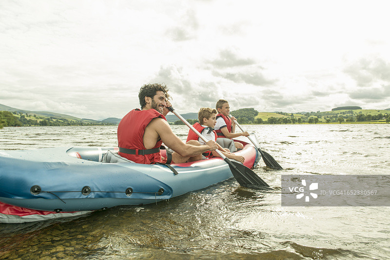 一名男子和两个男孩划着皮划艇离开了威尔士巴拉湖的岸边图片素材