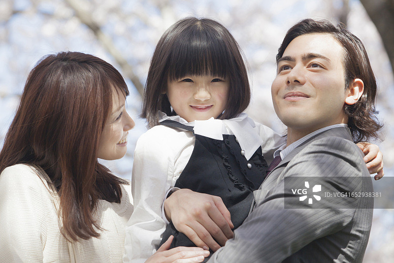 一个日本家庭站在一排樱花树前图片素材