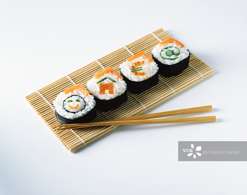 三文鱼寿司放在餐垫上，用木筷子夹着图片素材