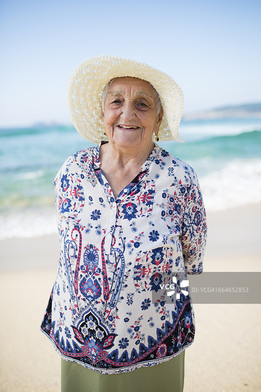 微笑的老妇人站在海滩上的肖像图片素材