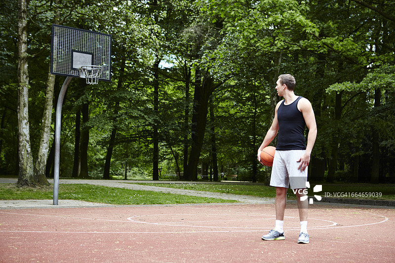 年轻的男篮球运动员在他的肩膀上看篮球框图片素材