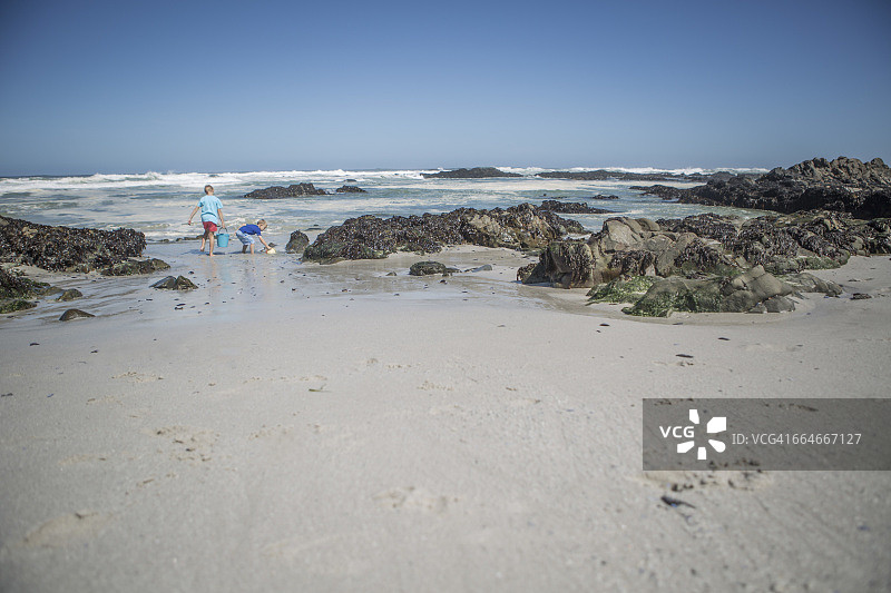 两个男孩在南非开普敦的海滩上玩水桶图片素材