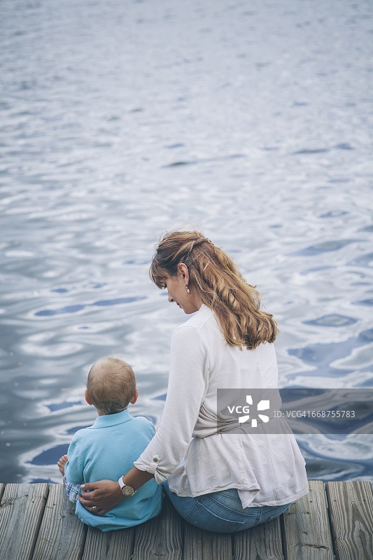 女人和儿子(18-23个月)坐在防波堤上图片素材